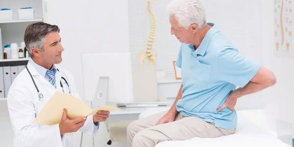 A man with back pain is consulting a chiropractor.