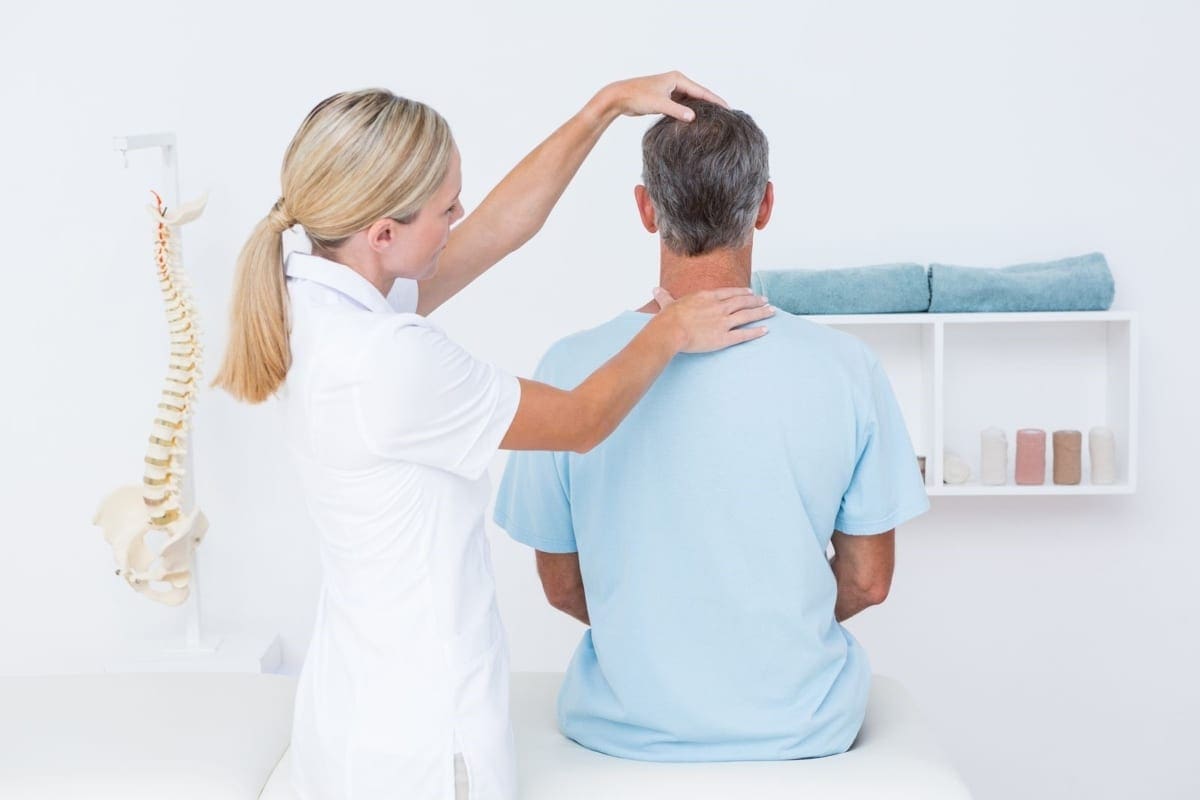 A chiropractor treats a man's neck.