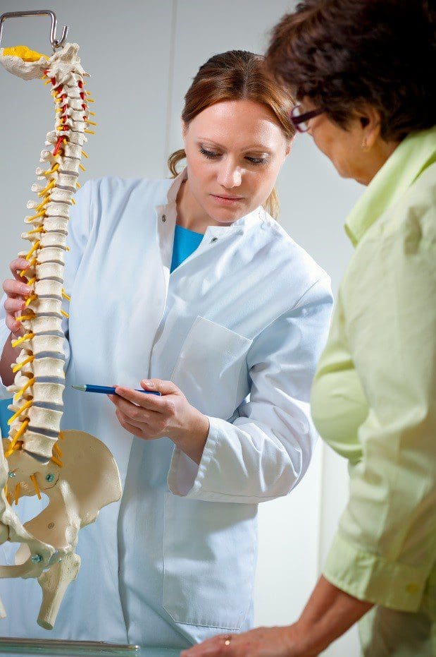 A chiropractor explains treatment using a model spine.