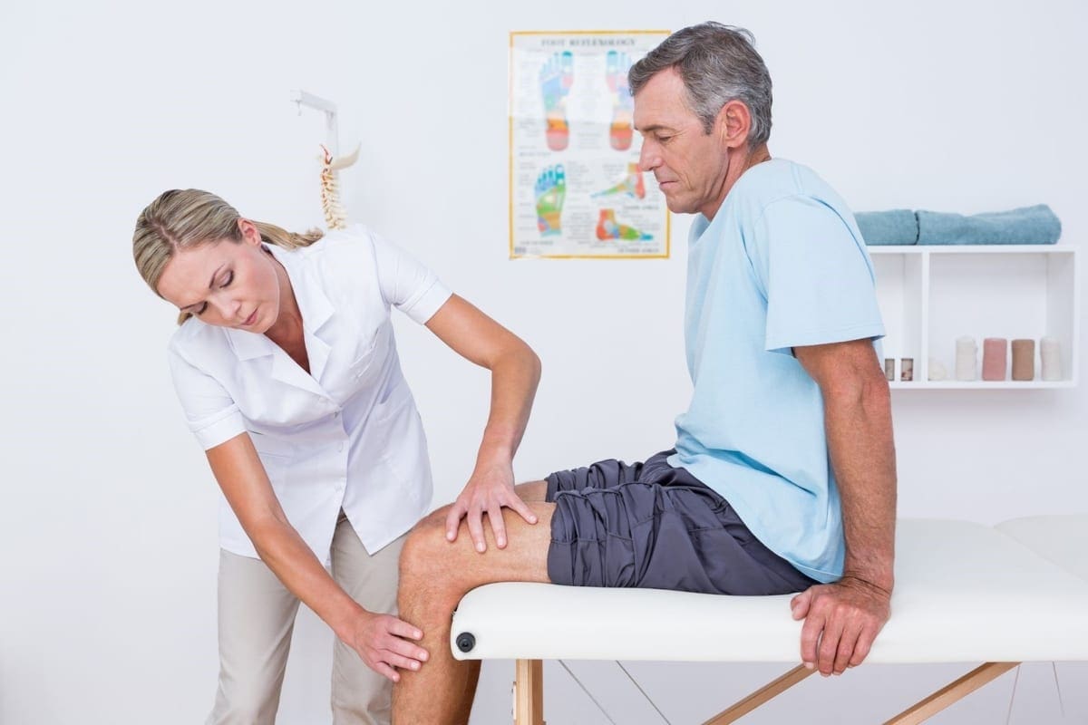 A chiropractor is administering treatment on a man's knee.
