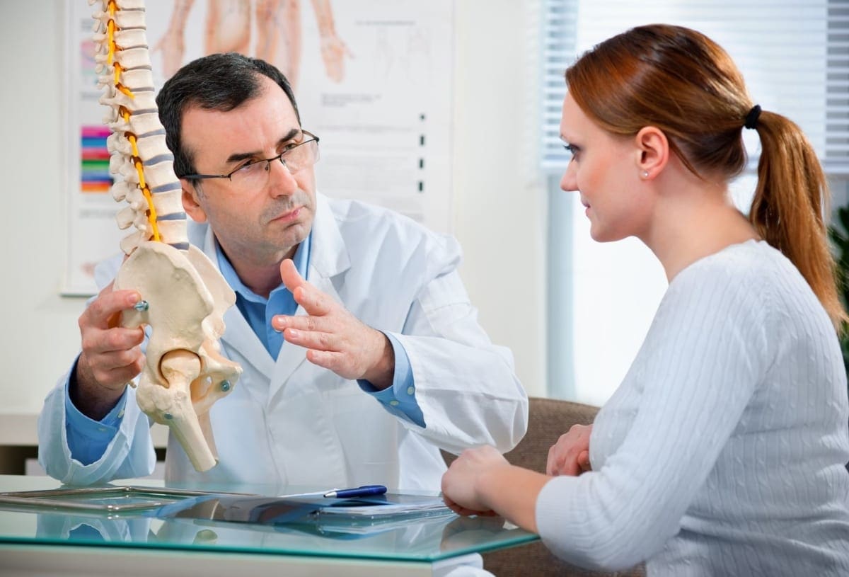A chiropractor discusses the cause of pain and treatment options with a patient.