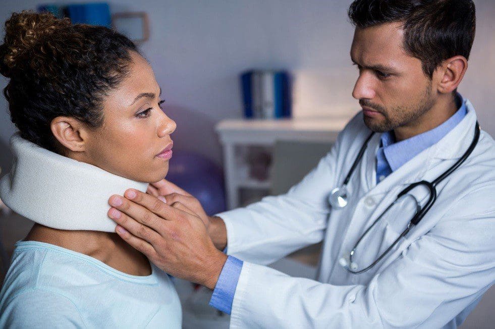 A chiropractor examines a woman's neck injury.