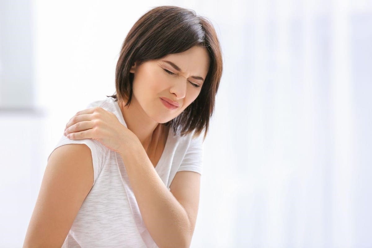 A woman hunches over because of Soft Tissue injuries in the shoulder.