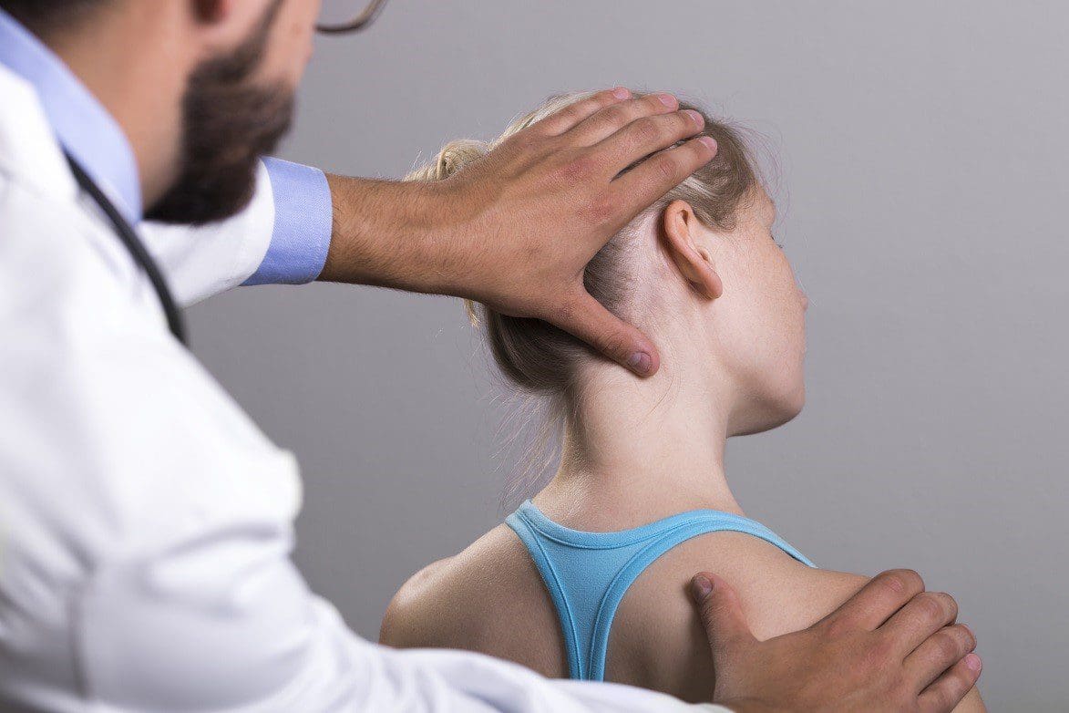 A chiropractor administers a neck adjustment to treat whiplash on a female patient.