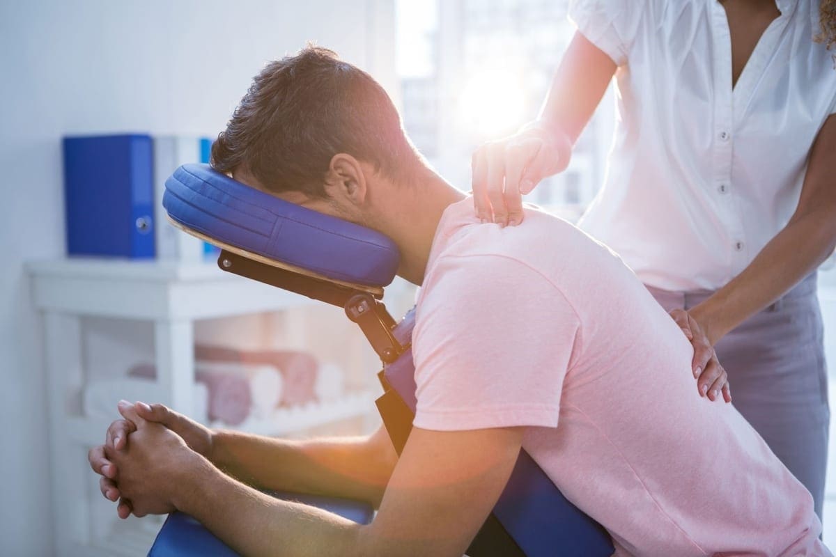 A man is receiving chiropractic treatment for upper back and shoulder pain.