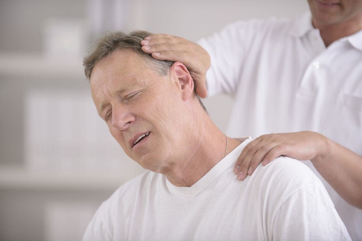 A chiropractor adjusts a mans neck to relieve neck pain.