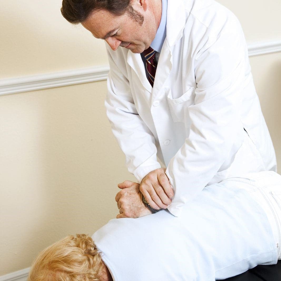 A chiropractor conducts a spinal adjustment Session with his patient.