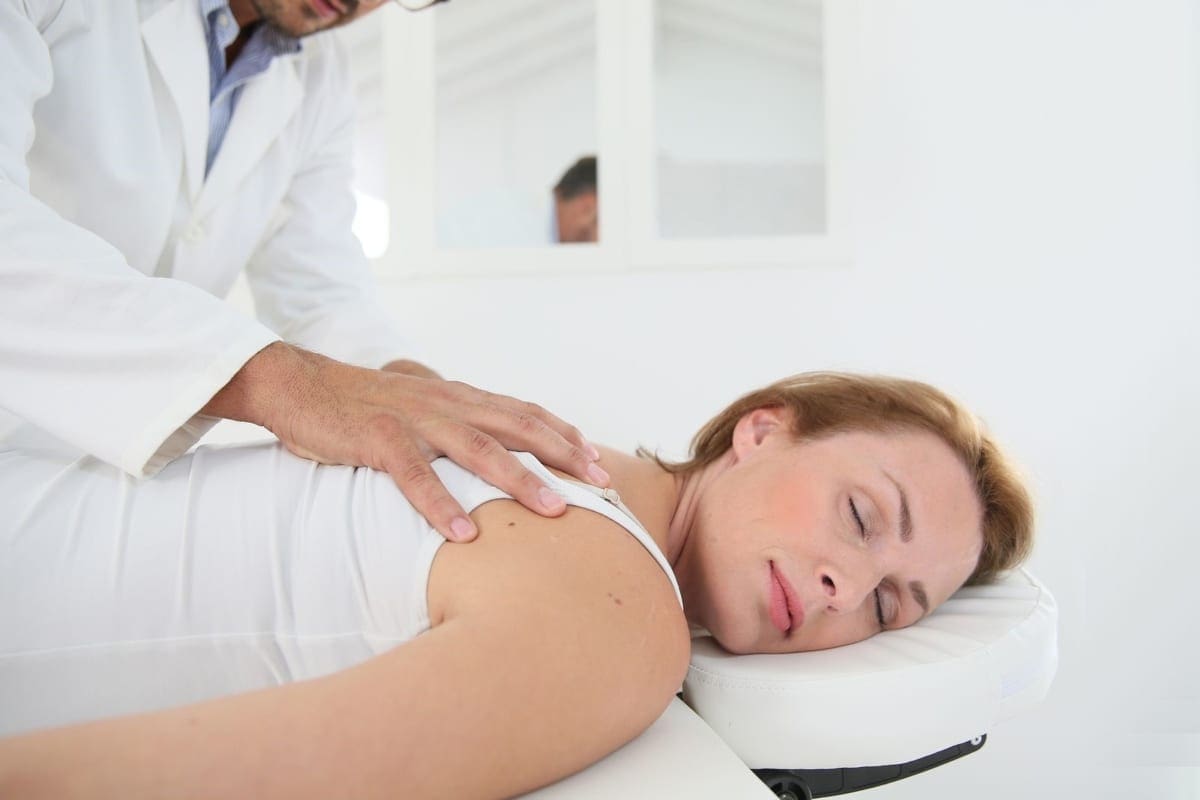 A woman lays on a chiropractic table for an adjustment to relive asthma symptoms.