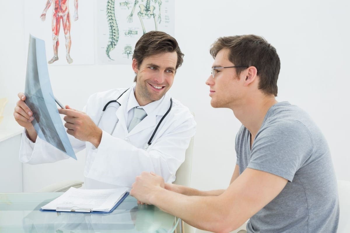 A Chiropractor goes over a treatment plan with a man during his first chiropractic appointment.