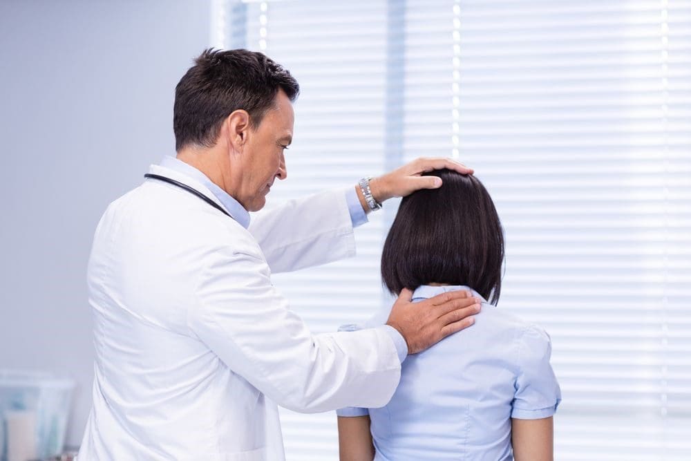 A woman's neck is being examined and treated by a chiropractor to relieve pain.