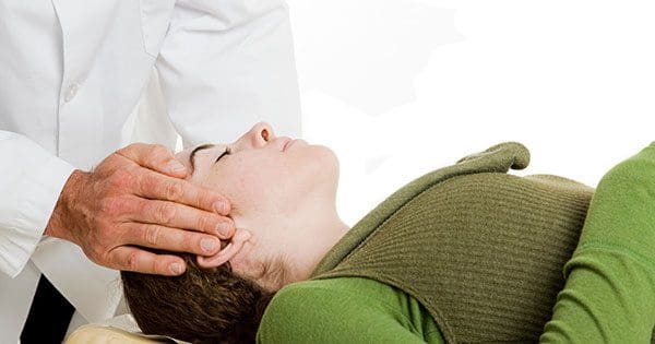 A woman being treated by a chiropractor for headaches.
