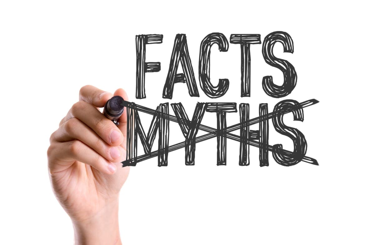 A hand holding a marker writing "Facts" and "Myths". "Myths" is scratched out.