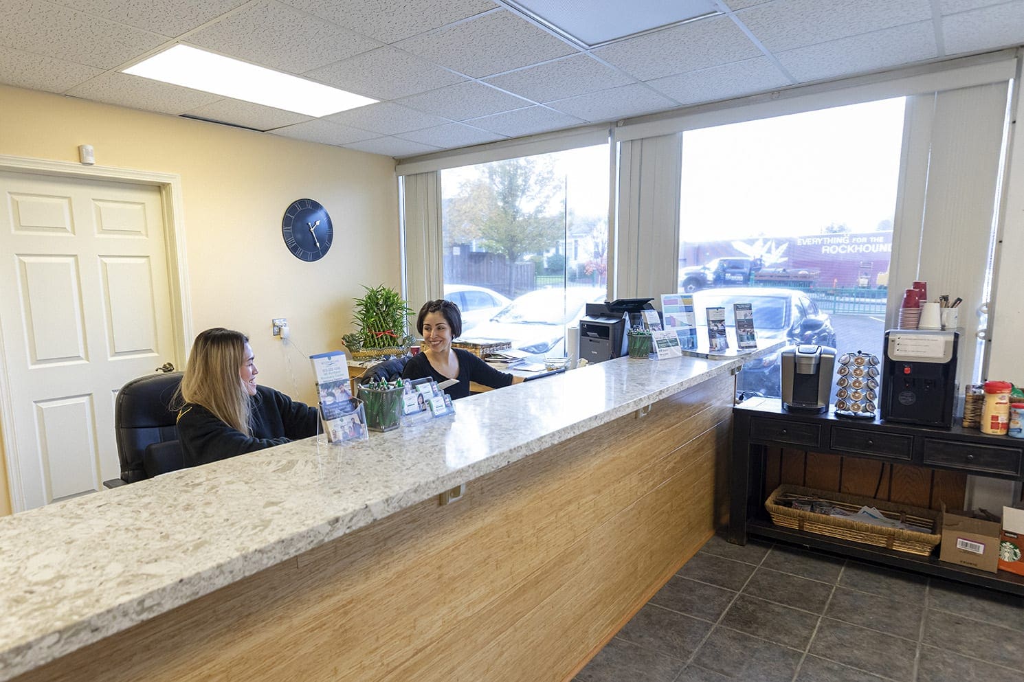 Two receptionists sit at the front desk of a chiropractic clinic.