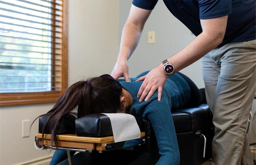 A woman is laying face down on a massage table while a message therapist administers massage therapy in Hillsboro.