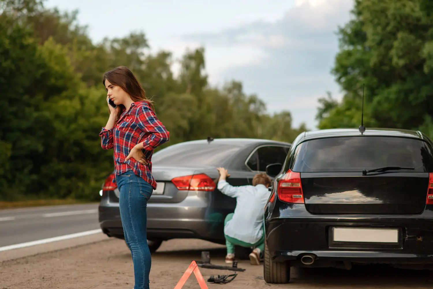 Two people examine the damage to their cars after an auto accident.