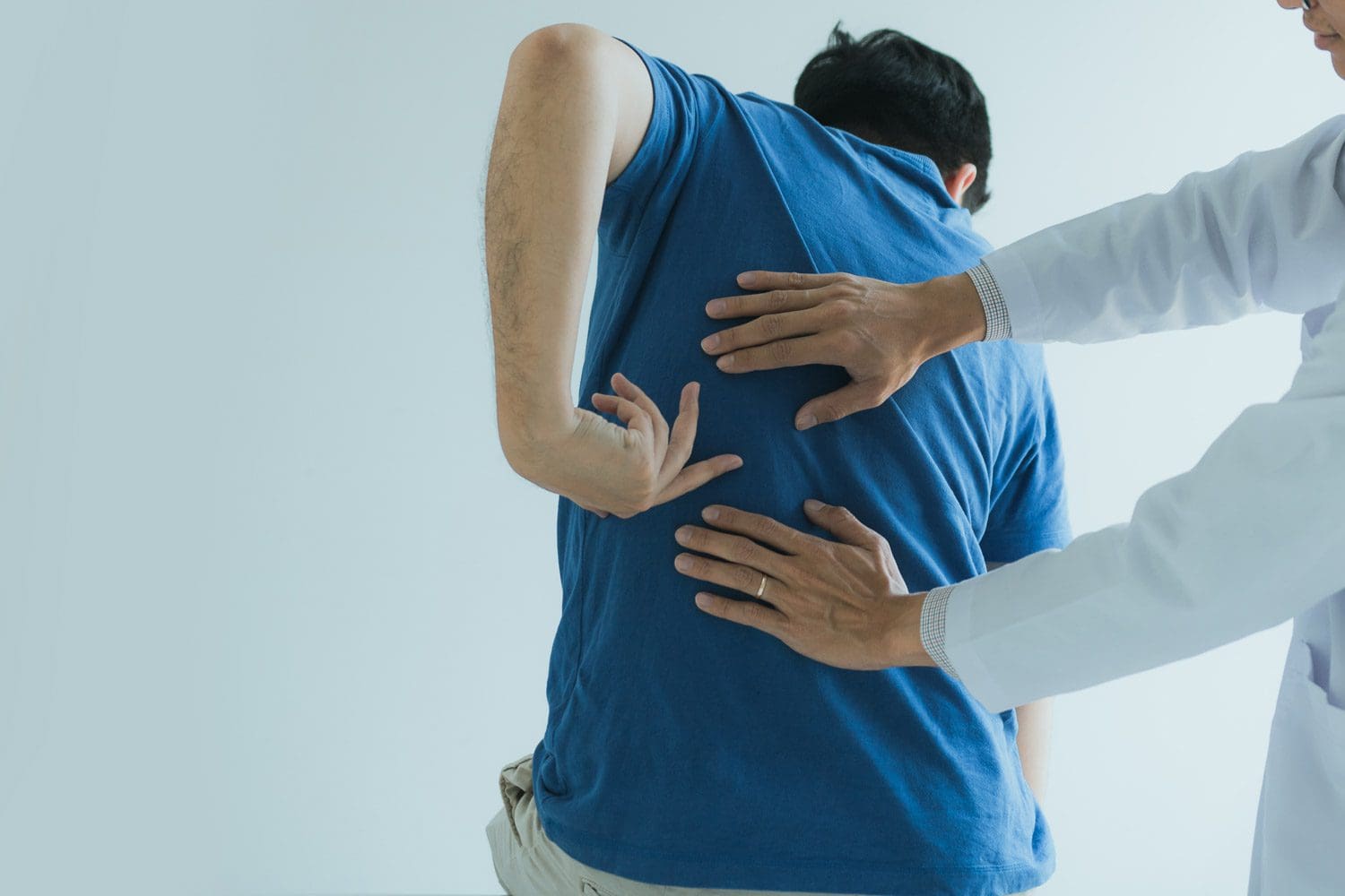 A chiropractor in Tigard examines a man's back to provide treatment for back pain relief.