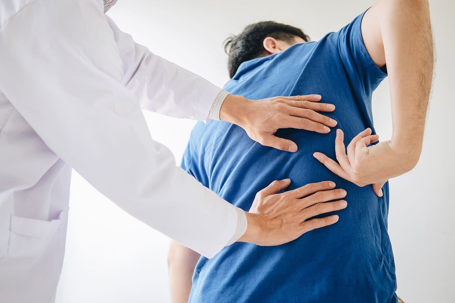A chiropractor examines a patients lower back to determine treatment for back pain.