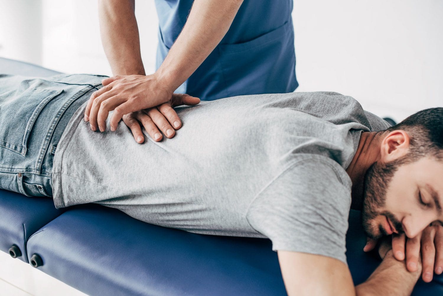 A Vancouver Chiropractor administers a back adjustment on a male patient.