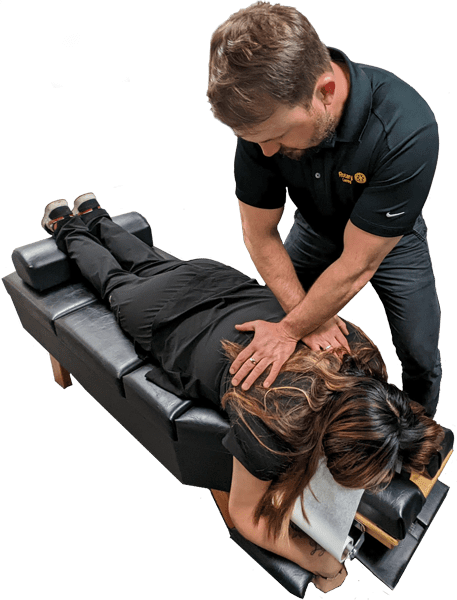 Dr. Matt Fryauf, D.C. administering a spinal adjustment on female patient lying on chiropractic table.