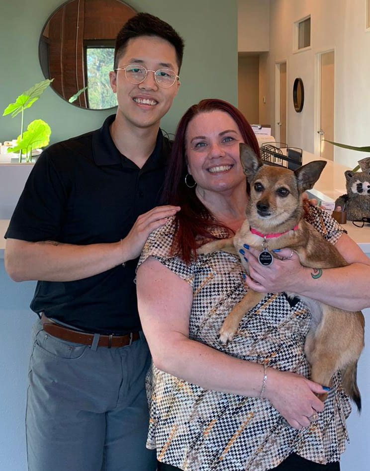Dr. David H. Rong, D.C. with smiling female patient and her dog after recovery from auto injury treatment.