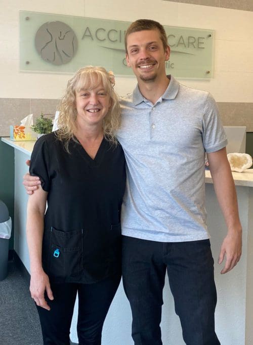 Dr. Nik Predtechensky, D.C. with arm around a female patient who is smiling after auto injury chiropractic treatment.