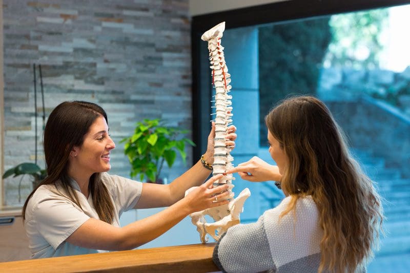 A chiropractor uses a model of the human spine to explain herniated disc injuries and treatment.
