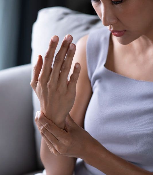 A woman massages her hand because she is experiencing numbness and tingling.