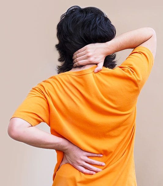 An image of the spine is transposed on top of a photograph of a man's back, to show how causes of back pain.