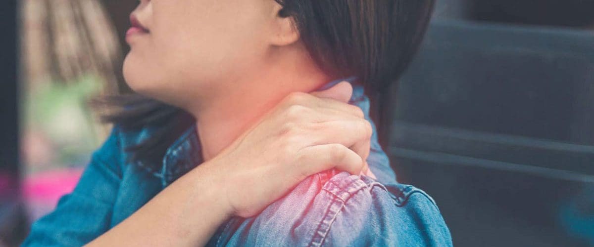 A woman is massaging her left shoulder because of shoulder pain.