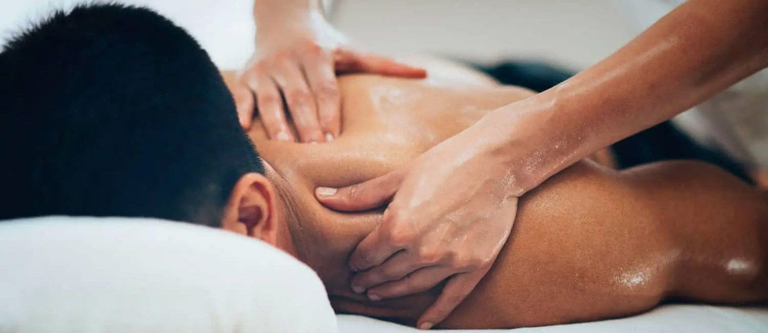 a man laying face down on a massage table receiving a massage from a chiropractic massage therapist