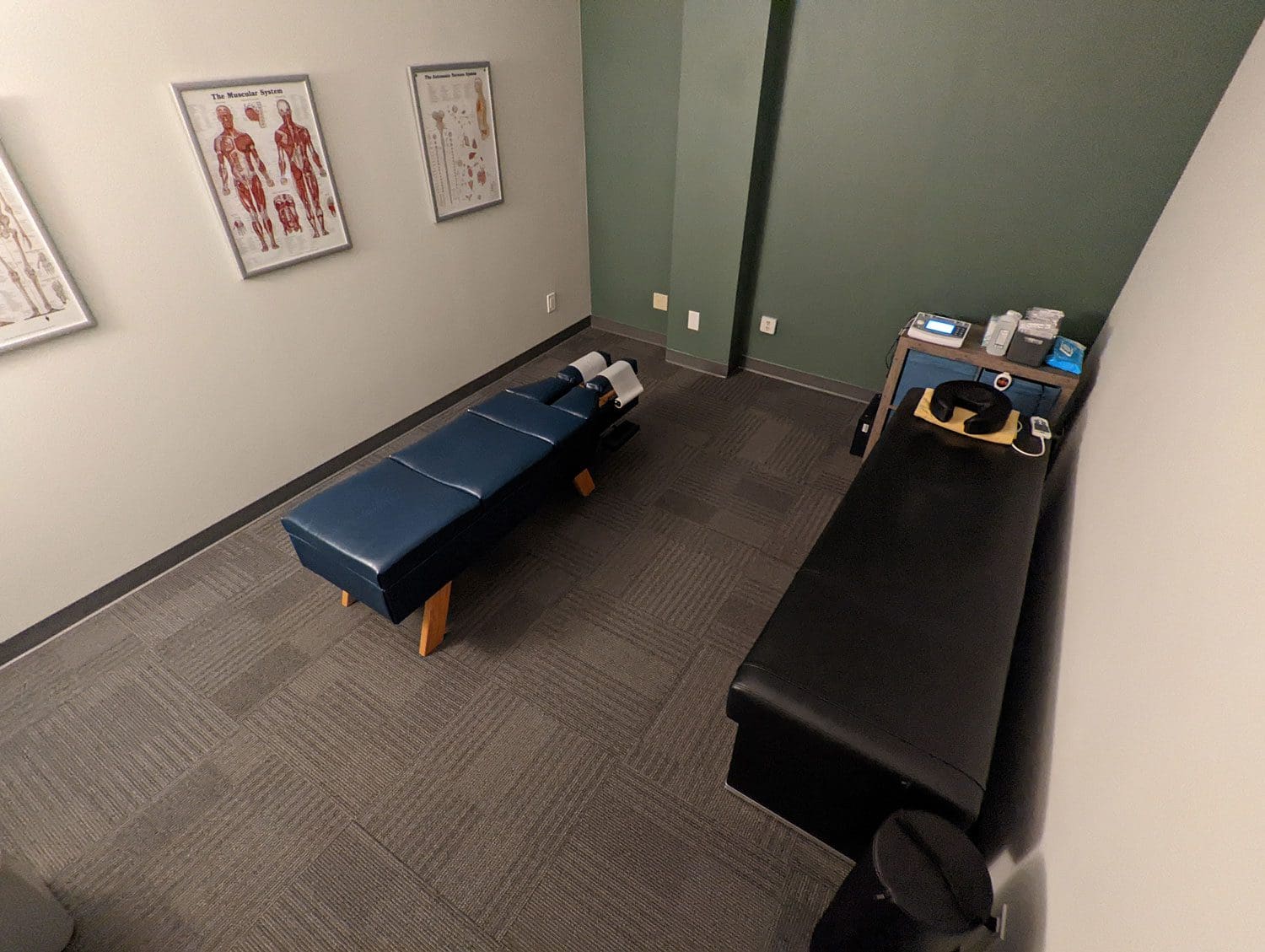 Woodburn Chiropracitc treatment room with adjustment table and framed art of the musculoskeletal system.