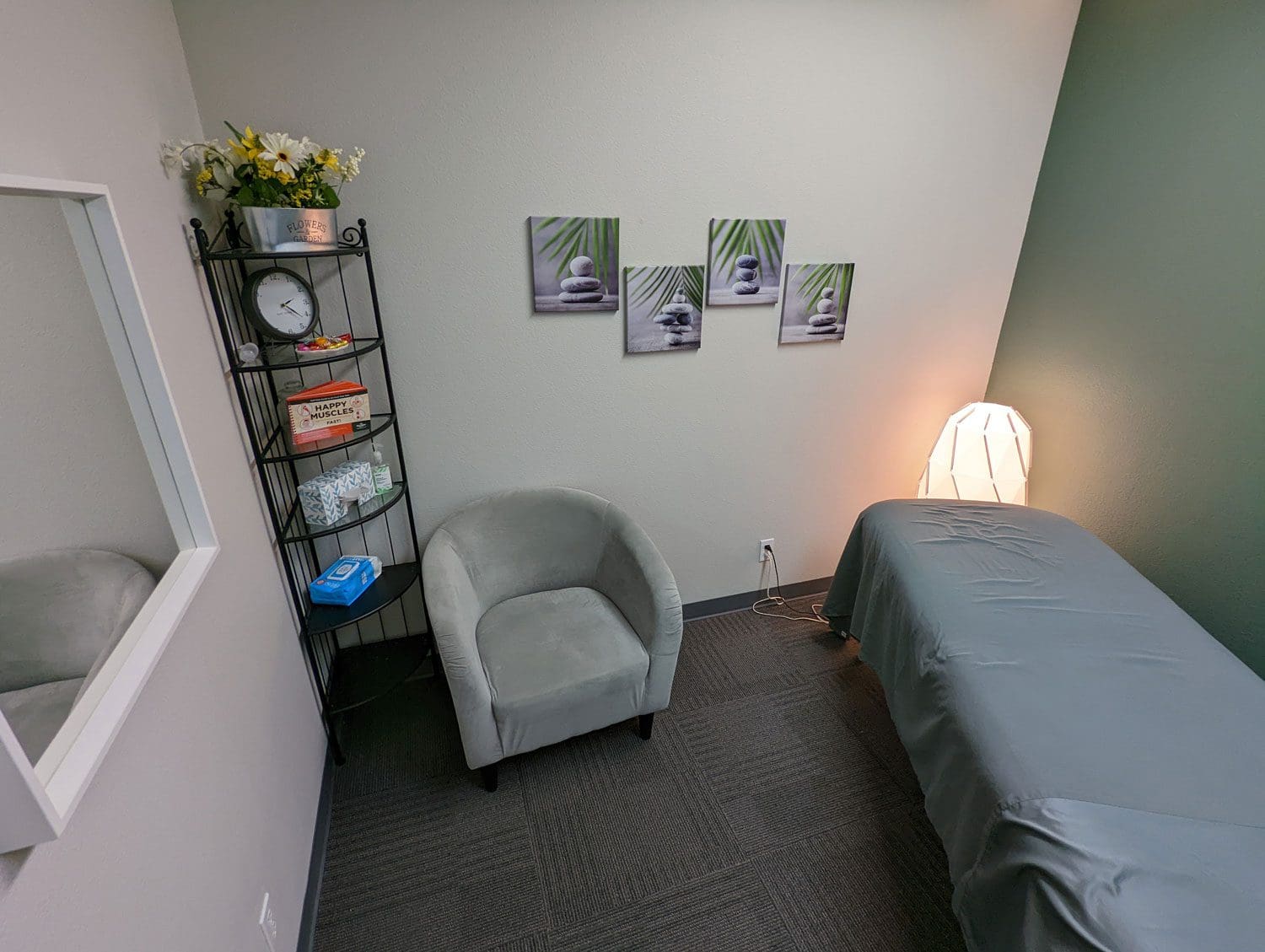 Woodburn massage therapy room with massage table and sitting chair.