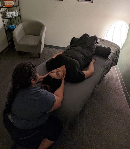 A woman is laying on her back getting a massage.