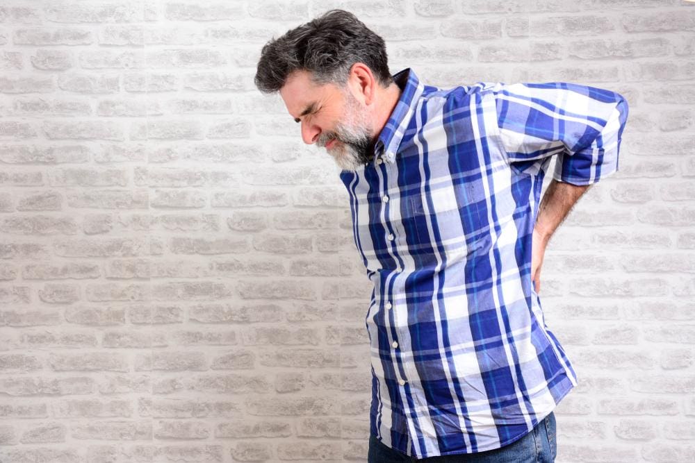 A man leans experiencing middle back pain.