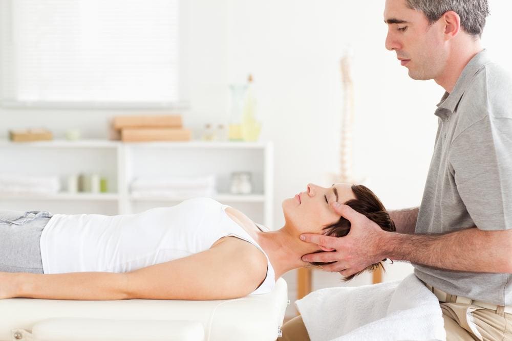 A woman is laying on a chiropractic table getting a neck adjustment for post accident whiplash.