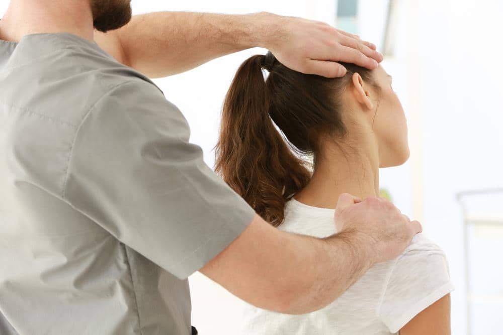A woman is getting a chiropractic neck adjustment to treat whiplash.