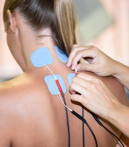 Electrical stimulation pads are being placed in a woman's neck and upper back.