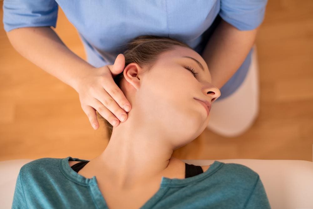 A woman is receiving a chiropractic neck adjustment to treat post car accident whiplash injuries.