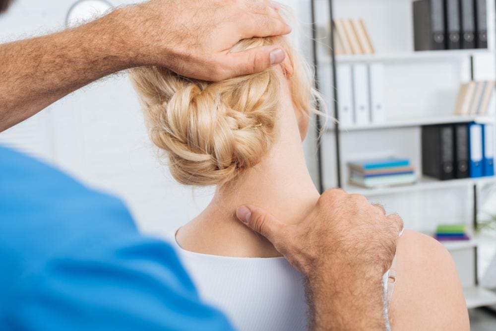 A woman getting a chiropractic neck adjustment to treat whiplash.