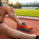 A man sits on a running track because his knee hurts from a knee injury.