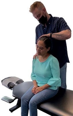 A chiropractor is administering a neck adjustment to a woman.