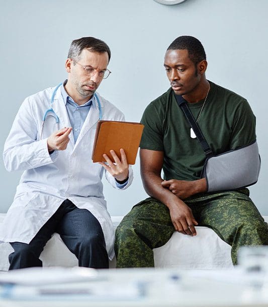 A man with an workplace injury to his arm discusses treatment options with his chiropractor.