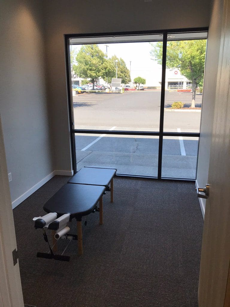 Bend Clinic adjustment room with chiropractic table floor to ceiling windows