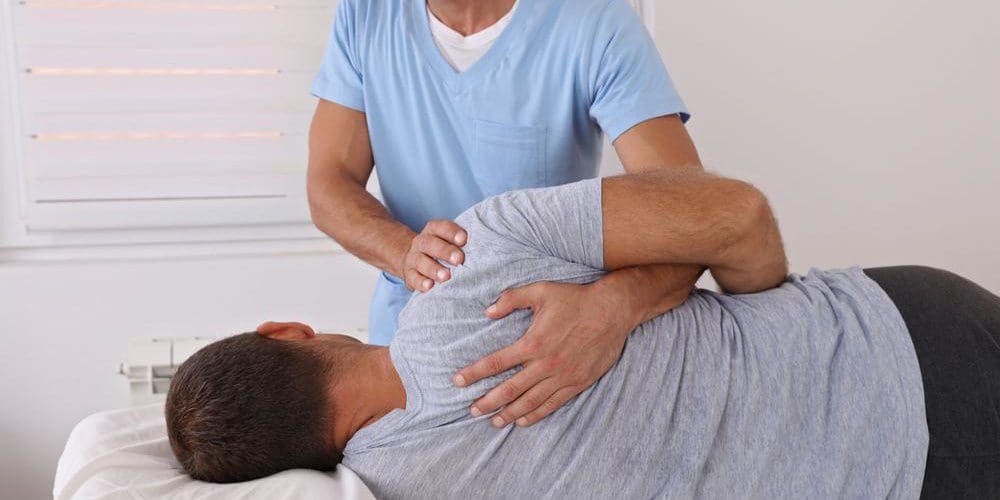 A chiropractor is treating a man for spine pain.