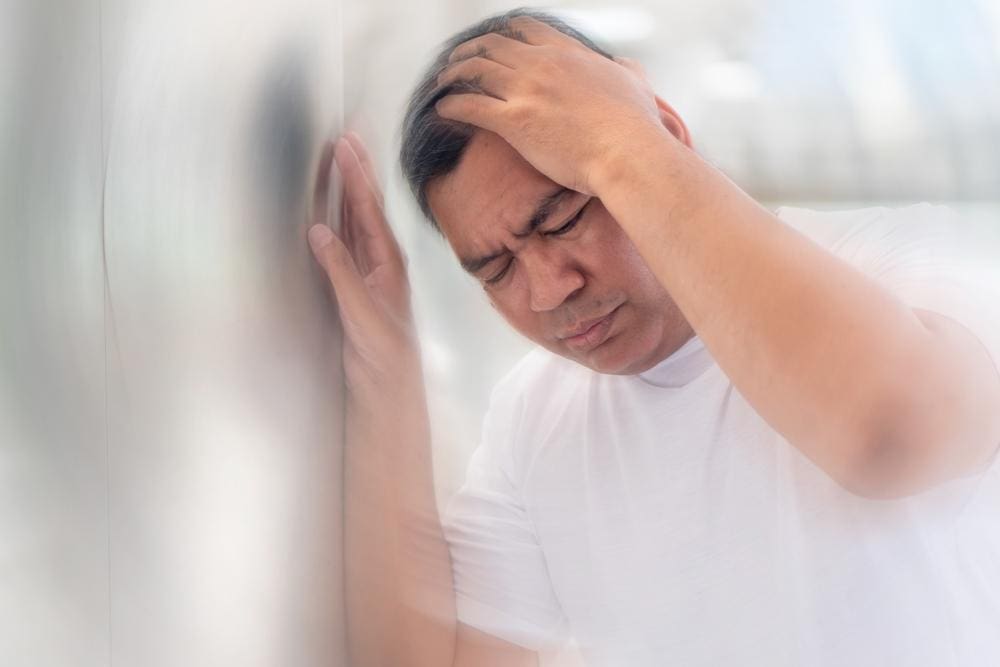 A man is holding his head because he is very dizzy.