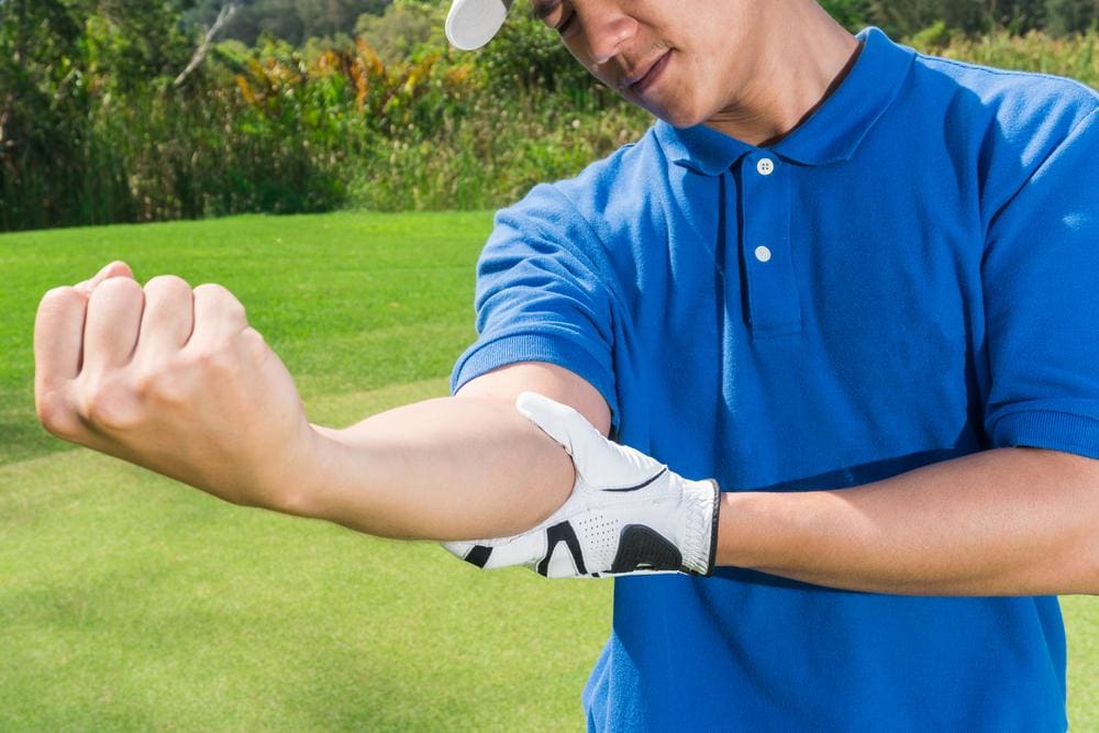 A golfer is holding his elbow because it is in pain.