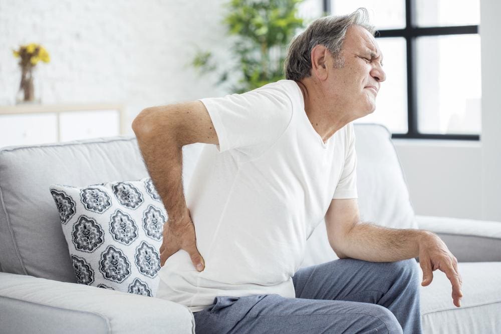 A man is having a hard time getting off the couch because of SI joint pain.