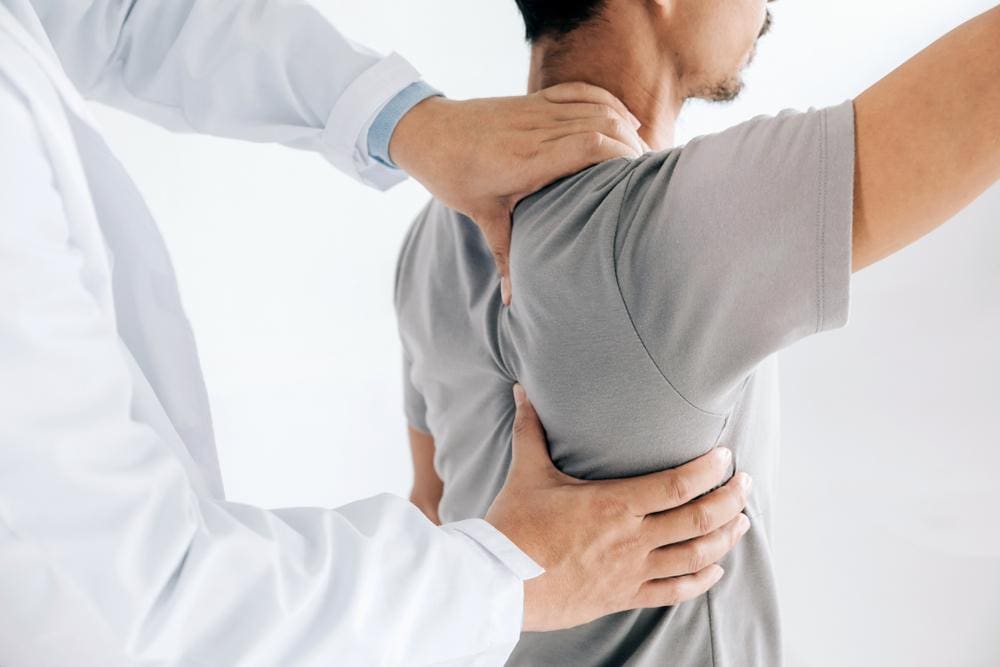 A chiropractor is examining a man's shoulder and collar bone to assess treatment. 