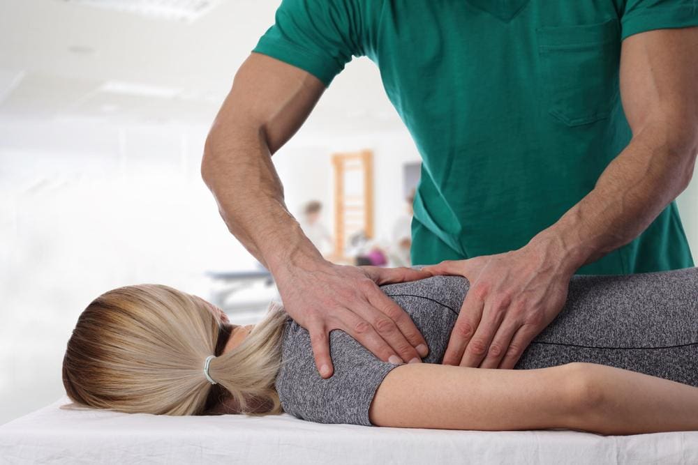 A woman is getting chiropractic adjustment for back stiffness.