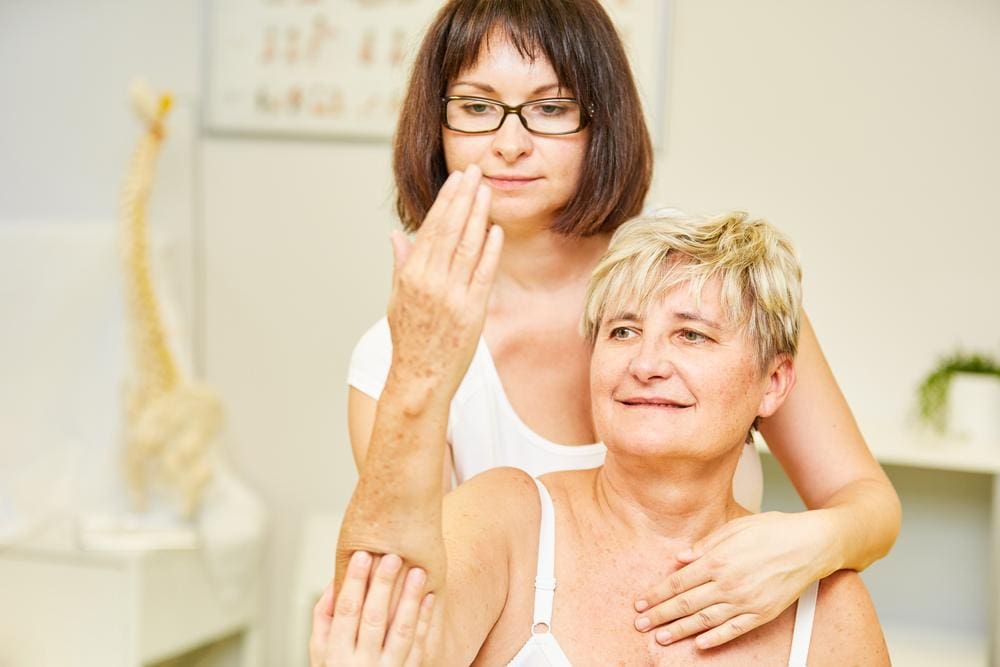 A chiropractor is treating a woman for pain caused by bursitis. 